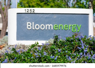 Blurred Bloom Energy sign in blooming landscape at headquarters in Silicon Valley. Company manufactures and markets solid oxide fuel cells that produce electricity on-site - Sunnyvale, CA, USA - 2020