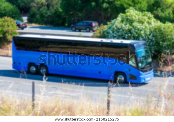 Blurred blue coach\
bus is driving on\
highway.