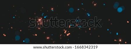 blurred blue and orange sparks from neon lights in front of black backgound