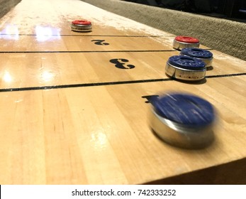Blurred blue shuffleboard disc skidding on the table, selective focus.