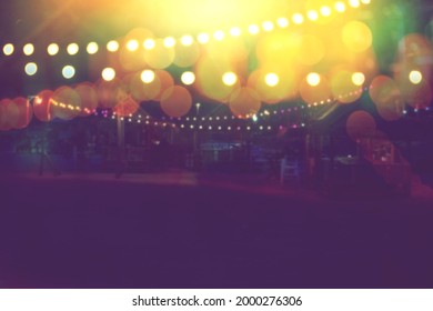 Blurred Bokeh Light With Yellow String Lights Decor In Beach Restaurant At Dusk Of Summer Background