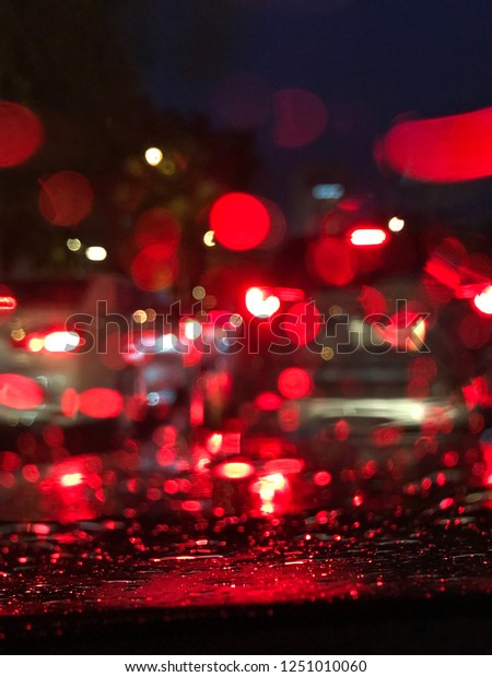 Blurred and bokeh tail light\
when traffic jam and rain take pictures on the car through the\
windshield.