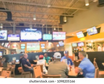 Blurred busy sports bars restaurants in USA. Large wall mount flat-screen TV, classic wooden table, chair. People drink craft beer, hanging out, watching sport. Happy Hour, night club concept