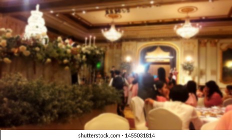 Blurred By The Bride And Groom Are Cutting The Cake On The Stage At The Wedding Reception At The Meeting Room In The Hotel. Family, Friends And Guests Sit Down For Dinner At A Luxury Hotel.