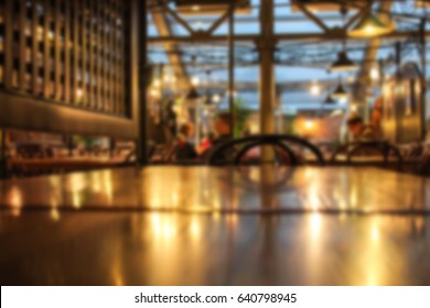 Blurred Cafe Interior With Some People On A Background. Coffee House Blur Background. Evening Time.