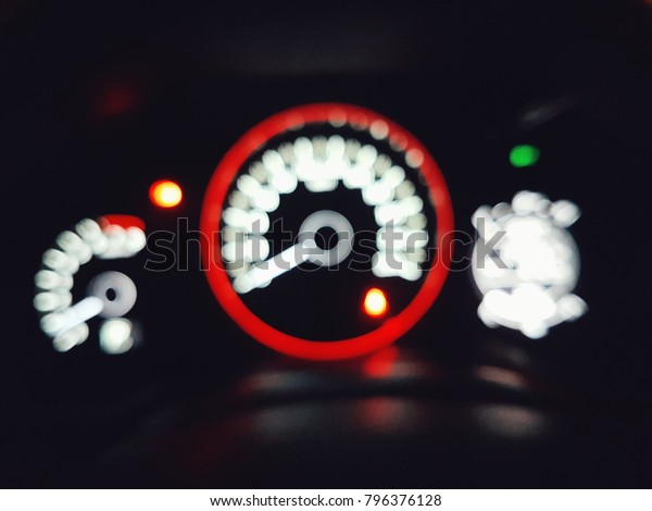 Blurred car dashboard with modern\
indicators and gauge. Blurry vision of drunken driver at\
night