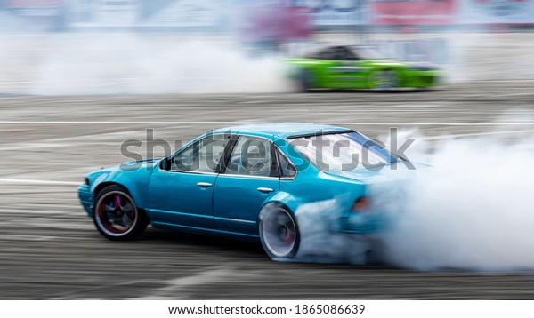 Blurred car drifting, Two car\
drifting battle on asphalt street road race track, Automobile and\
automotive drift car with smoke from burning tire on speed\
track.