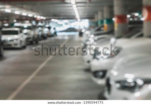 Blurred car parking building\
with a lot of cars occupied the parking lot during the operating\
hour