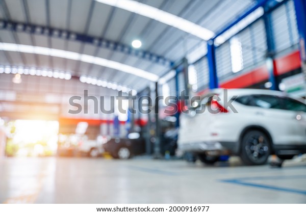 blurred of car repair\
station paved with epoxy floor and electric lift for a car that\
comes to change the engine oil in the background of maintenance car\
service center.
