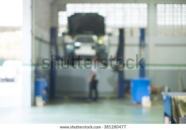 Blurred of car technician repairing the car in\
garage background, Interior of a car repair station,Cars servicing\
at Service station,car mechanic work at repair service station\
garage,vintage color.