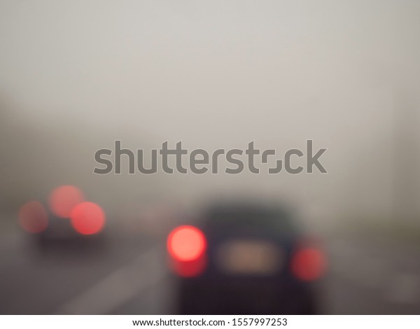 Blurred car traffic in dangerous low visibility\
conditions in a fog.. 