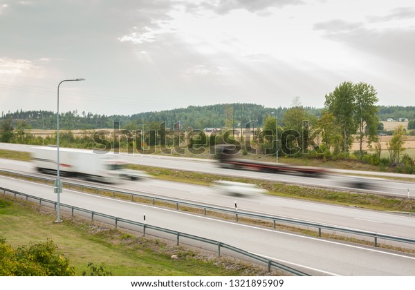 Blurred cargo cars in motion. Asphalt roads with\
cars at autumn in\
Finland.