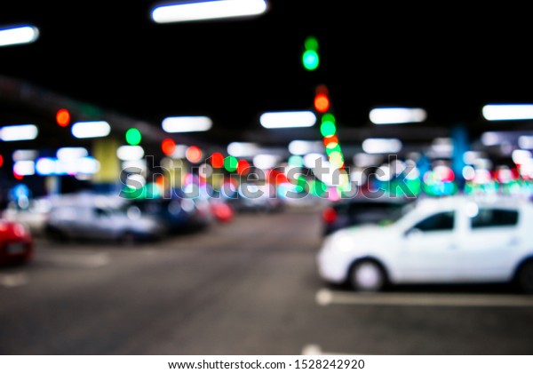 Blurred cars in car parking lot\
in shopping mall. Bokeh lights background. Abstract blur car\
parking lot for background. Blurred cars parking and bokeh light\
concept