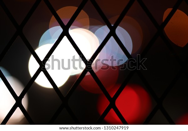 Blurred\
cars on an expressway as seen through a\
fence.
