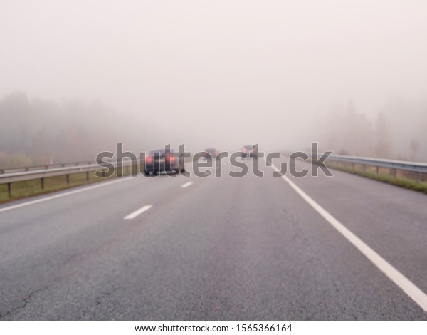 Blurred cars on a road in a fog, concept\
danger, driving in low visibility\
condition.