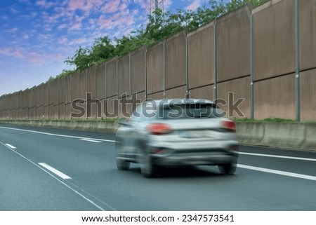 Blurred cars on the sound absorbing tunnel at the asphalt road. Metal structure with plastic parts.