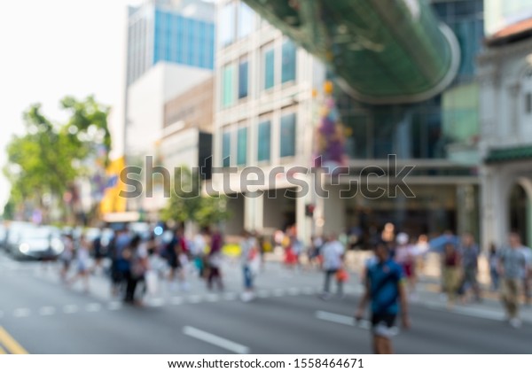 Blurred cars stop at traffic lights for\
pedestrians to cross Orchard road in Singapore.\
