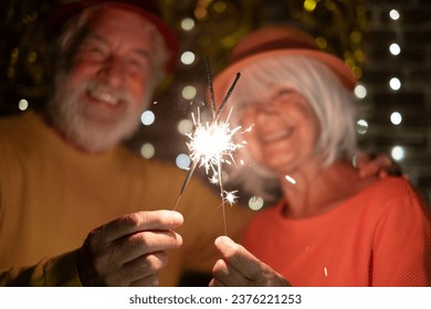 Blurred caucasian senior couple holding sparklers celebrating new year. Happy lifestyle for mature retirees, party lights