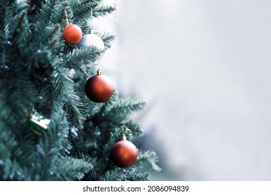 Blurred christmas tree and red ball with white space background in cool tone. out of focused red christmas ball hanging on tree with copy space.