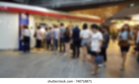 Blurred Of City People Getting In Line For Buying Train Ticket In Evening After Working Day At Ticket Vending Machine On Platform, Which Is Nearby Shopping Center,office Building And Business Area.