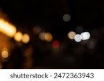 A blurred city street image at night. Abstract blur urban city street road with lighting bokeh for background. There is noise in the photo due to lack of light.