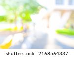 BLURRED CITY STRET WITH GREEN TREE LEAVES IN SUN LIGHT, MODERN DEFOCUSED URBAN BACKGROUND, CITYSCAPE AT SPRING TIME