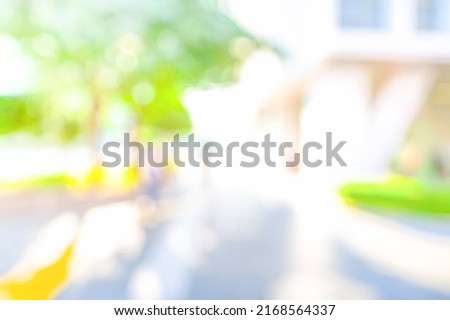 BLURRED CITY STRET WITH GREEN TREE LEAVES IN SUN LIGHT, MODERN DEFOCUSED URBAN BACKGROUND, CITYSCAPE AT SPRING TIME
