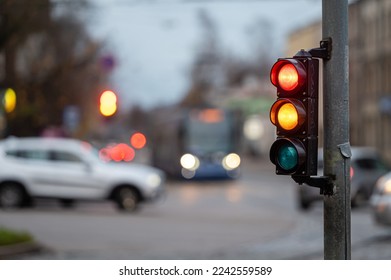 blurred city traffic with traffic lights, in the foreground a semaphore with a red and orange light - Powered by Shutterstock