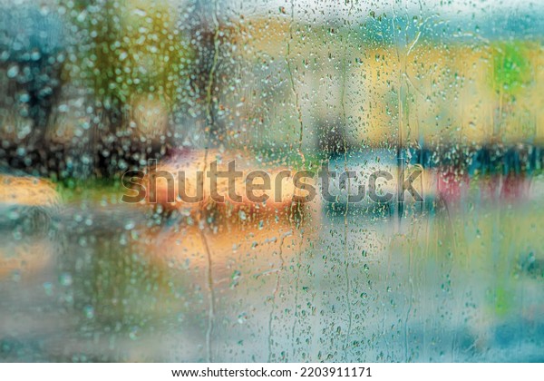 Blurred city view from window, rain drops, evening
street traffic, car at
night