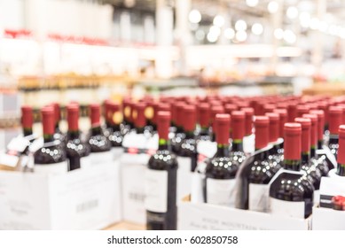 Blurred And Close Up View Group Of Red Wine Bottles In Cellar At Wine Section Of Modern Distribution Warehouse. Inventory, Logistic, Business, Wholesale, Export Concept. Beverage Alcohol Background.