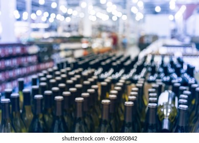 Blurred And Close Up View Group Of White Wine Bottles In Cellar At Wine Section Of Modern Distribution Warehouse. Inventory, Logistic, Business, Wholesale, Export Concept. Beverage Alcohol Background.