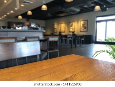 Blurred Coffee Shop Or Pub Background And Perspective View Of Wooden Table Corner 