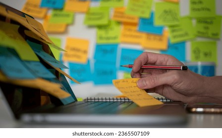 blurred colorful post note background, man using pencil and computer laptop working on memo note memorandum in office, reminder messages for working schedule, things to do list