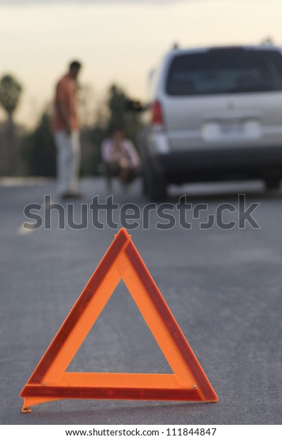 Blurred couple in discussion with warning\
triangle in foreground
