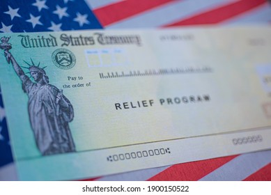 Blurred COVID-19 economic Stimulus American rescue program check on blurred USA flag and sun light background. Relief program concept. 
