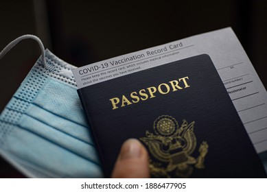 Blurred COVID-19 Vaccination Record card, Passport of USA and Medical Mask. Immune passport or certificate for travel concept. 