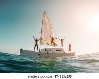 Blurred crazy friends diving from sailing boat into the sea - Young people jumping inside ocean in summer vacation - Travel and fun concept - Fisheye lens distortion - Defocused image
