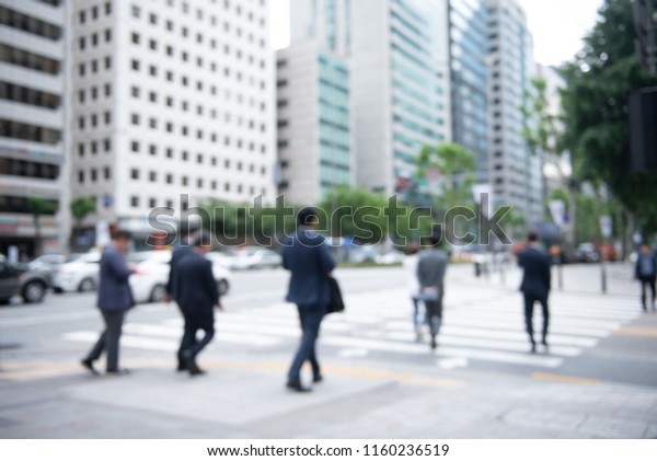 Blurred crowd of anonymous people,\
commuters on pedestrian waiting for traffic light and crossing the\
street on zebra crossing in the city, Seoul,\
Korea