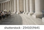 Blurred crowd with columns in vatican city depicting people visiting italy with an out-of-focus background and architectural serenity during a sunny day.