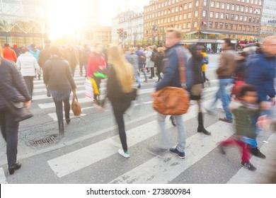 Blurred crowd of people walking on zebra crossing in Copenhagen in late afternoon. Some of them also bring a bike, typical mode of transport in the city. Unrecognizable faces. 