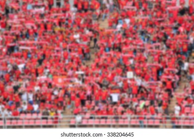 Blurred Crowd Of Spectators On A Stadium With A Football Match.