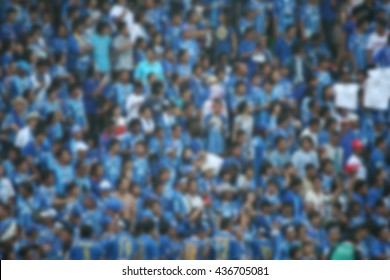 Blurred Crowd Of Spectators On A Stadium With A Football Match.