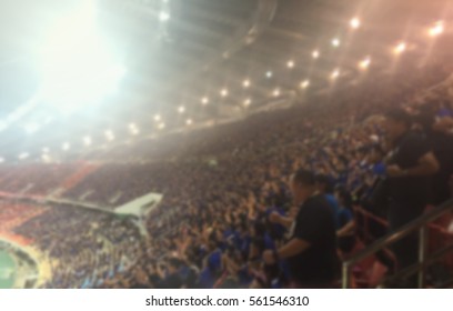 Blurred Crowd Of Spectators On A Stadium With A Football Match.