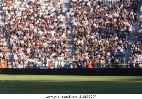 Blurred crowd of spectators on a stadium tribune at\
a sporting event
