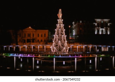 Blurred Decorated Christmas Tree Outside In Park  With Lights.New Year's Street Scenery In The Evening.Blurred And Magic Background.Decorated Christmas Tree In A City Park.