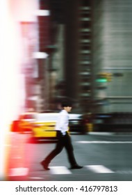 Blurred Defocused Abstract Image Of Man On Zebra Crossing In Urban Business Area, Manhattan, NYC. Man Hurrying About Their Business. Image In Motion Blur Style. Cross Process Stylization.