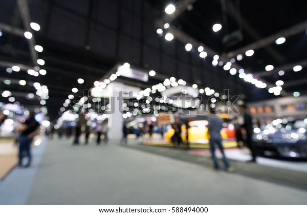 Blurred, defocused background of public event\
exhibition hall showing cars and automobiles, business commercial\
event concept.