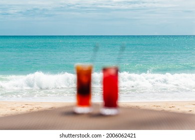 Blurred Defocused Fresh Exotic Cocktails on Table, Holidays in Paradise Concept. Iced Raspberry and Orange Drinks with Turquoise Sea Background. Healthy Berry Mocktails in Ocean Restaurant. No focus.