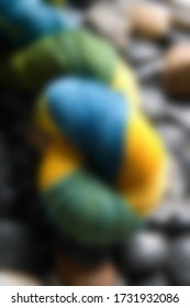 Blurred defocused hand dyed hank skeing ball of yarn wool.  Blue, yellow and green colour