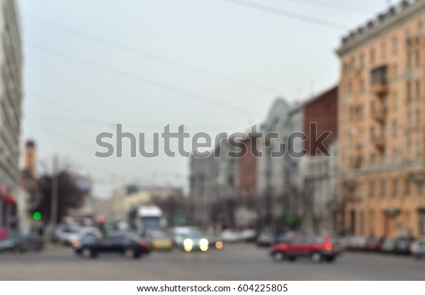 Blurred and defocused landscape with a city road\
during traffic. A lot of cars drive along the road in the middle of\
the city in the evening\
time